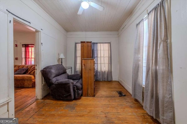 living area featuring wood-type flooring, ceiling fan, and a healthy amount of sunlight