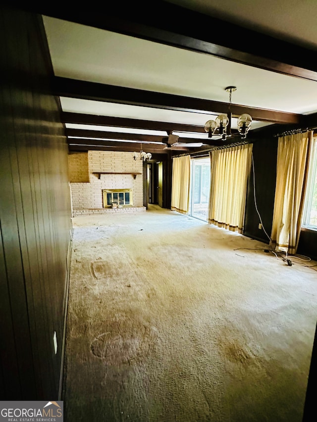 unfurnished living room with carpet flooring, wood walls, beamed ceiling, and a fireplace