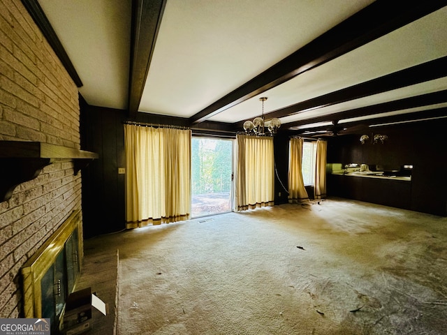 unfurnished living room with carpet, a notable chandelier, beam ceiling, and a fireplace