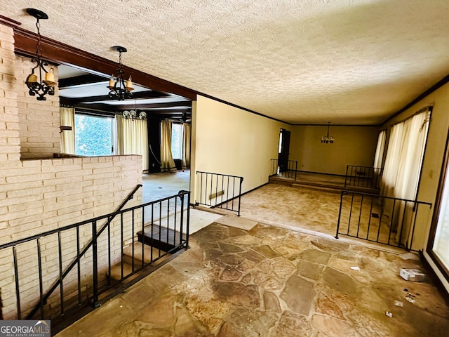 interior space with a textured ceiling, a notable chandelier, and beam ceiling