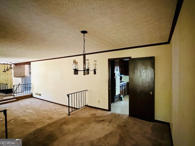 unfurnished dining area with ornamental molding, a textured ceiling, a chandelier, and carpet flooring