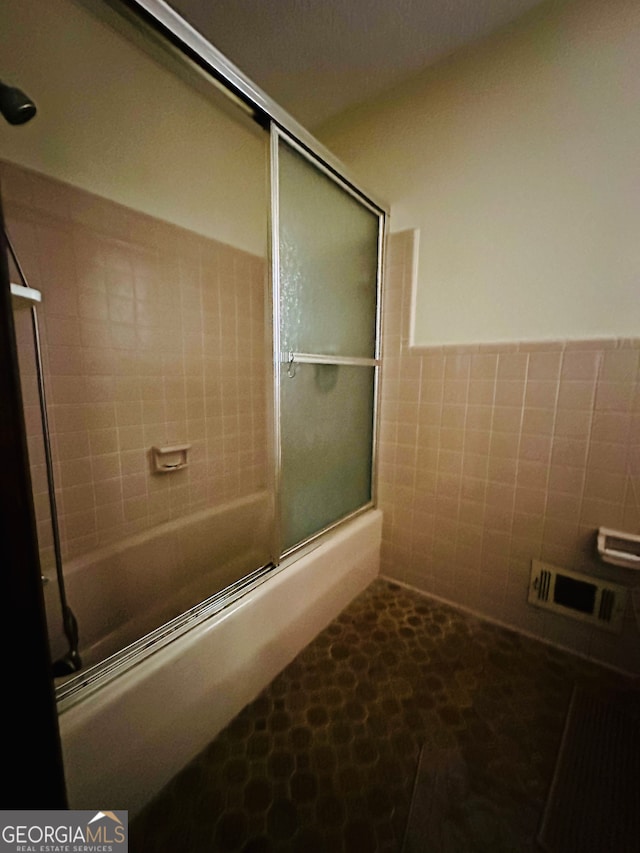 bathroom featuring tile walls and enclosed tub / shower combo