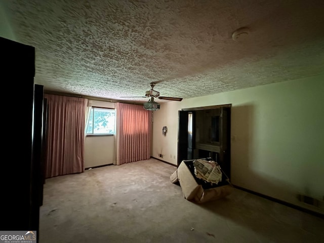 unfurnished bedroom with a textured ceiling, carpet flooring, and ceiling fan