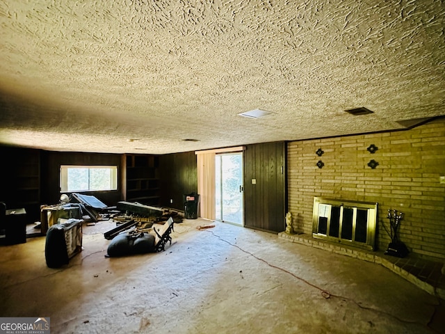 interior space with a textured ceiling, concrete floors, wooden walls, and a fireplace