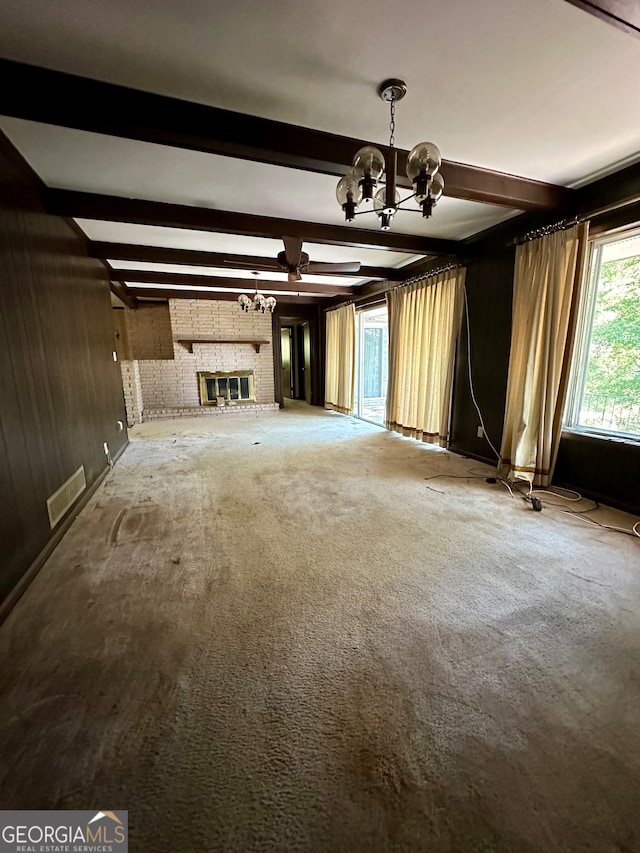 unfurnished living room with a fireplace, a chandelier, and beamed ceiling