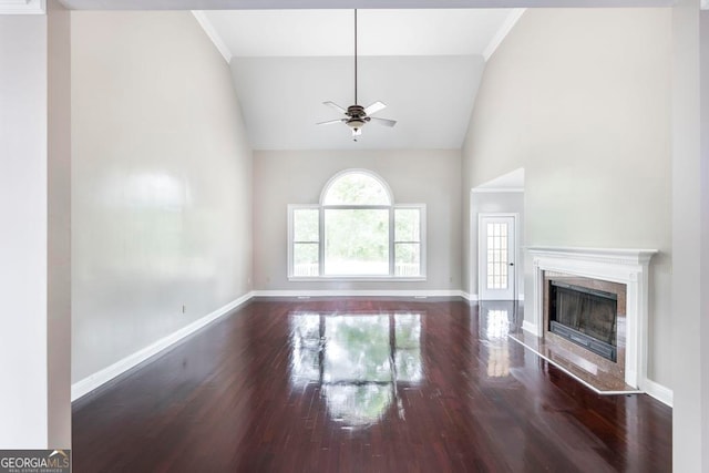 unfurnished living room featuring a high end fireplace, dark wood-type flooring, ornamental molding, lofted ceiling, and ceiling fan