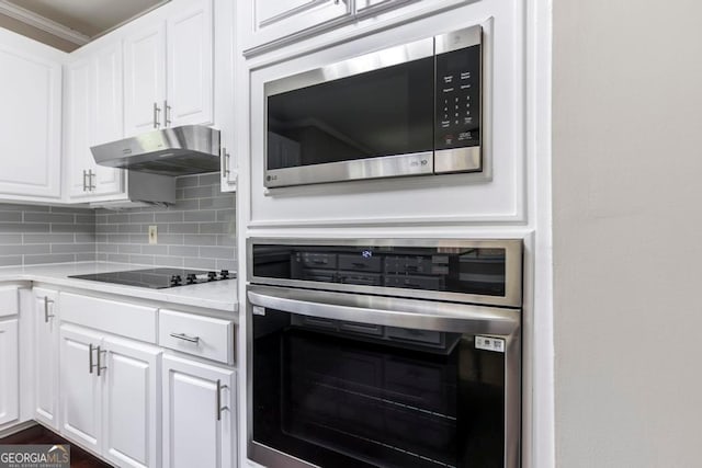 kitchen featuring stainless steel appliances, ornamental molding, white cabinets, and tasteful backsplash