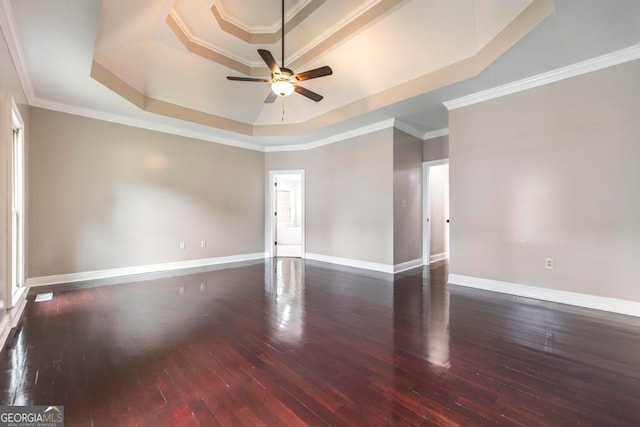 empty room featuring crown molding, a raised ceiling, ceiling fan, and dark wood-type flooring