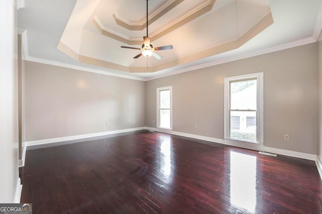 unfurnished room with plenty of natural light, ceiling fan, dark hardwood / wood-style floors, and a tray ceiling