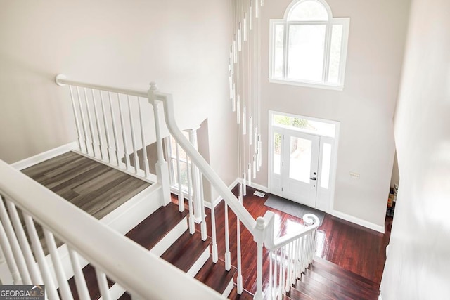 stairs with a high ceiling and hardwood / wood-style floors