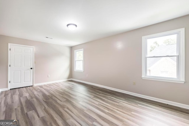 spare room with a healthy amount of sunlight and hardwood / wood-style flooring