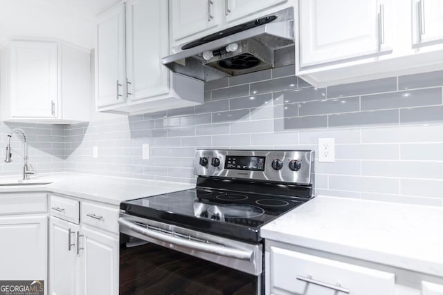 kitchen featuring tasteful backsplash, electric range, white cabinetry, and sink