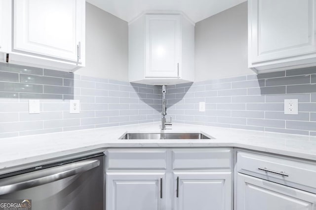 kitchen featuring stainless steel dishwasher, sink, white cabinets, and tasteful backsplash