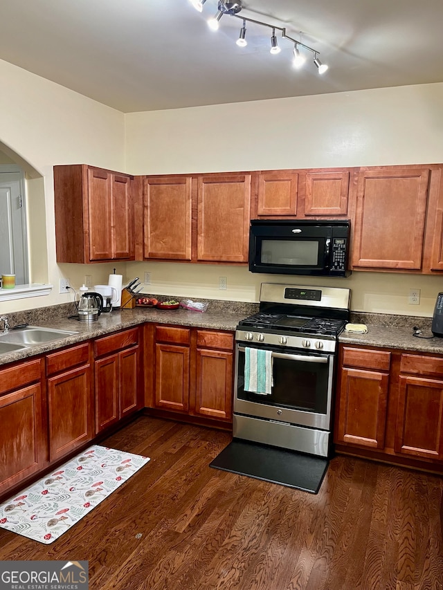 kitchen featuring dark wood-type flooring, stainless steel gas stove, track lighting, and sink