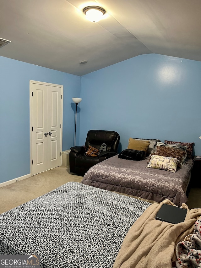 carpeted bedroom with vaulted ceiling and a closet