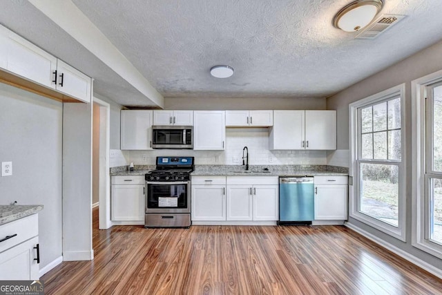 kitchen featuring hardwood / wood-style floors, backsplash, stainless steel appliances, and sink