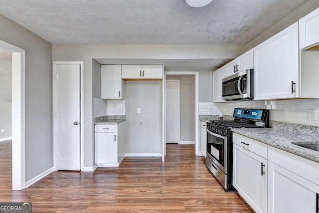 kitchen featuring appliances with stainless steel finishes, white cabinetry, and hardwood / wood-style flooring