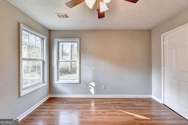 spare room with a textured ceiling, dark wood-type flooring, and ceiling fan