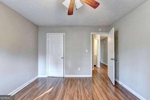 unfurnished bedroom with dark wood-type flooring, ceiling fan, and a textured ceiling