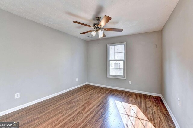 empty room with a textured ceiling, wood-type flooring, and ceiling fan