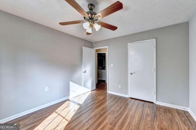 empty room with ceiling fan, dark hardwood / wood-style floors, and a textured ceiling