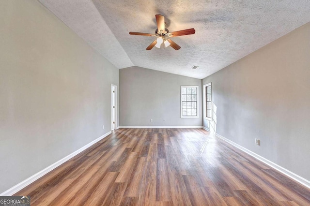 spare room with a textured ceiling, ceiling fan, vaulted ceiling, and dark hardwood / wood-style flooring