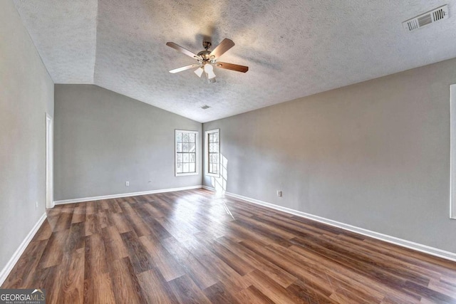 empty room with vaulted ceiling, a textured ceiling, dark hardwood / wood-style flooring, and ceiling fan