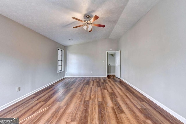 unfurnished room with dark wood-type flooring, ceiling fan, vaulted ceiling, and a textured ceiling