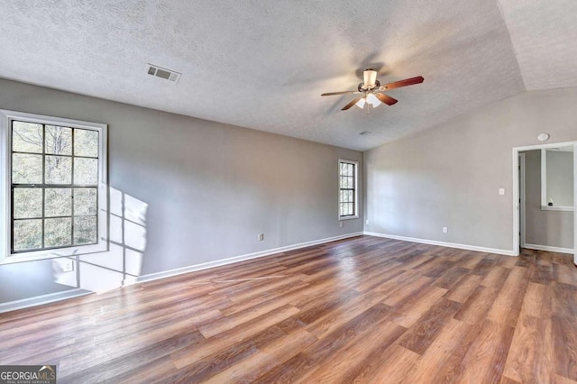 unfurnished room featuring lofted ceiling, hardwood / wood-style floors, ceiling fan, and a textured ceiling