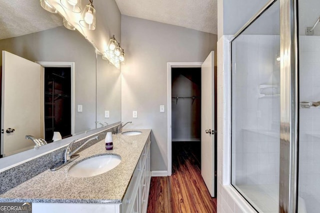 bathroom featuring an enclosed shower, lofted ceiling, wood-type flooring, vanity, and a textured ceiling