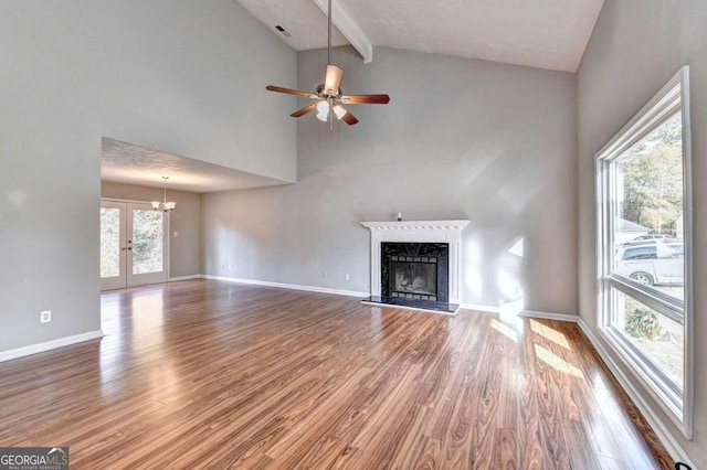 unfurnished living room with a fireplace, ceiling fan with notable chandelier, and plenty of natural light