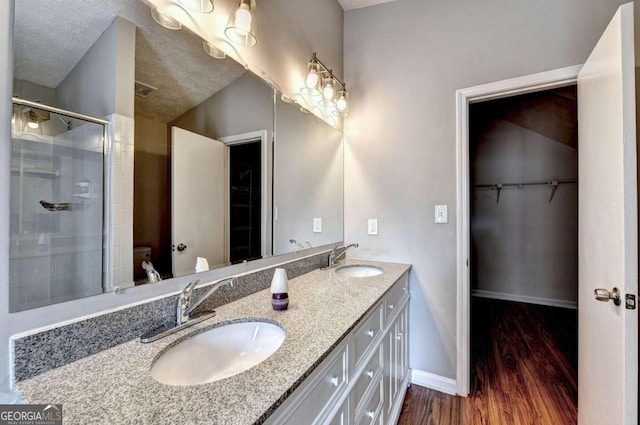 bathroom with a textured ceiling, vanity, vaulted ceiling, walk in shower, and hardwood / wood-style flooring