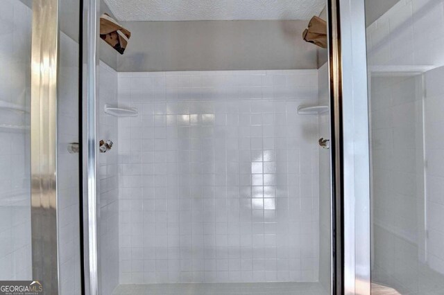 bathroom with a textured ceiling and a shower with shower door