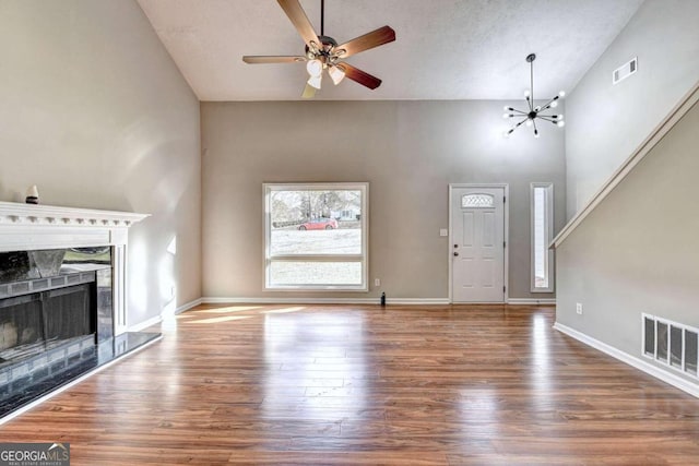 foyer entrance with high vaulted ceiling, hardwood / wood-style floors, and ceiling fan with notable chandelier