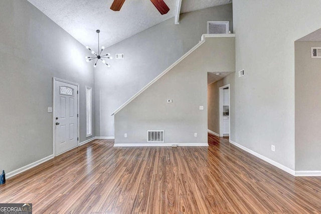 entryway with ceiling fan with notable chandelier, high vaulted ceiling, hardwood / wood-style flooring, and a textured ceiling