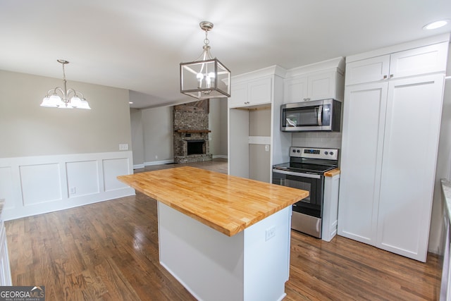 kitchen featuring dark wood-type flooring, stainless steel appliances, a chandelier, and white cabinetry