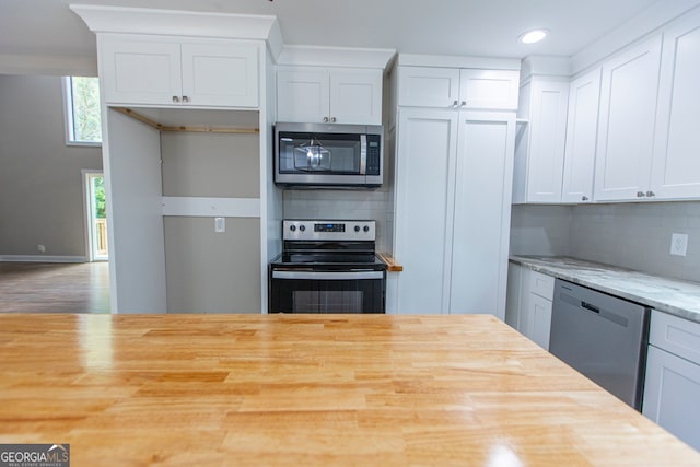 kitchen featuring appliances with stainless steel finishes, light stone counters, decorative backsplash, and wood-type flooring