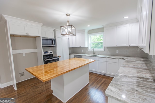 kitchen with appliances with stainless steel finishes, a center island, decorative backsplash, and dark wood-type flooring