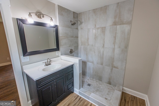 bathroom featuring vanity, a tile shower, and wood-type flooring