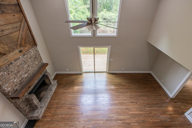 unfurnished living room with dark hardwood / wood-style flooring, a brick fireplace, and ceiling fan