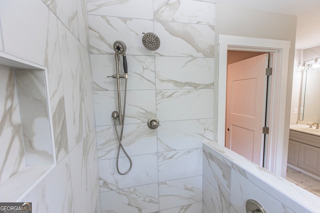 bathroom with a tile shower and vanity