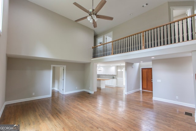 unfurnished living room with high vaulted ceiling, wood-type flooring, and ceiling fan