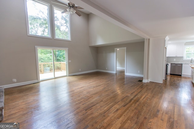 unfurnished living room featuring ceiling fan, dark hardwood / wood-style floors, and a towering ceiling