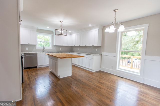 kitchen featuring a kitchen island, stainless steel dishwasher, wood counters, and white cabinets