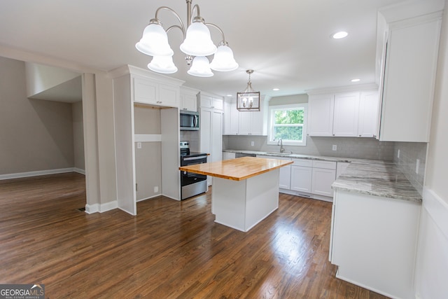 kitchen with a center island, wooden counters, appliances with stainless steel finishes, and white cabinetry