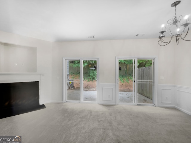 unfurnished living room featuring a notable chandelier and light carpet