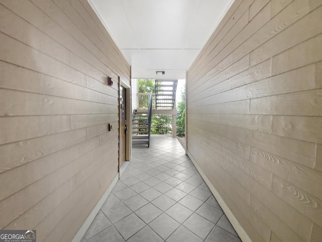 hallway featuring expansive windows, light tile patterned floors, wood walls, and a sunroom