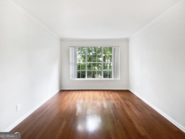 spare room with baseboards, wood finished floors, and crown molding