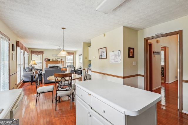 kitchen featuring a textured ceiling, hardwood / wood-style floors, white cabinets, and a kitchen island