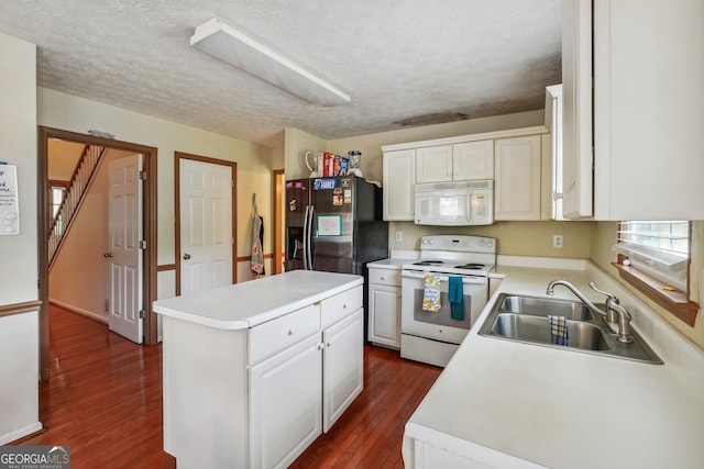 kitchen featuring white appliances, dark wood-type flooring, a center island, sink, and white cabinetry